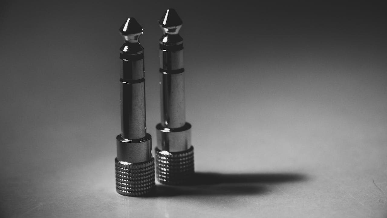 Black and white close-up of metallic audio jack connectors on a flat surface, showcasing modern technology.